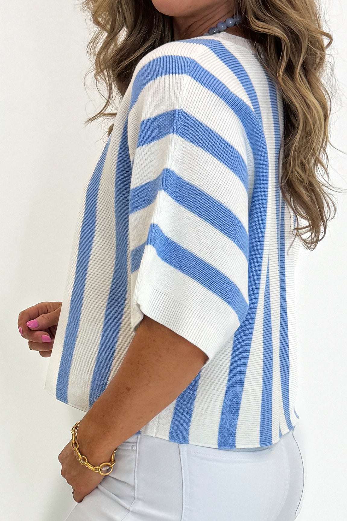 Side detail view of woman wearing Swagger Boutique’s Blue &amp; White Striped Short Sleeve Sweater by Entro with jeans against white studio background.