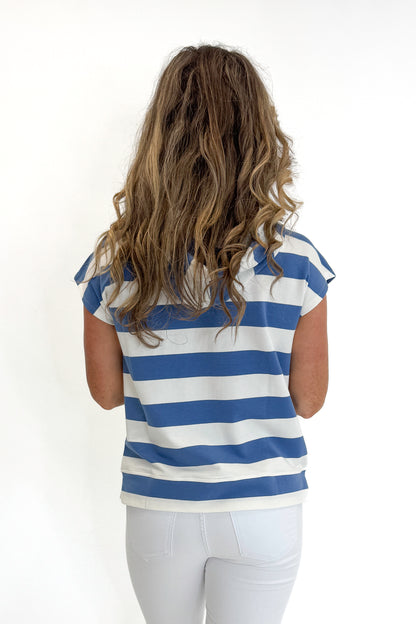 Back view of woman wearing Swagger Boutique’s Blue &amp; White Striped Sleeveless Sweatshirt with white jeans against white studio background.