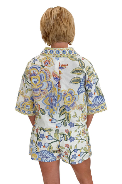 Back view of woman wearing Swagger Boutique’s Blue &amp; Yellow Floral Print Wrap Skort by Entro with matching top against white studio background.