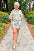 Front view of woman wearing Swagger Boutique’s Blue & Yellow Floral Print Wrap Skort by Entro with matching top walking outside down a path.