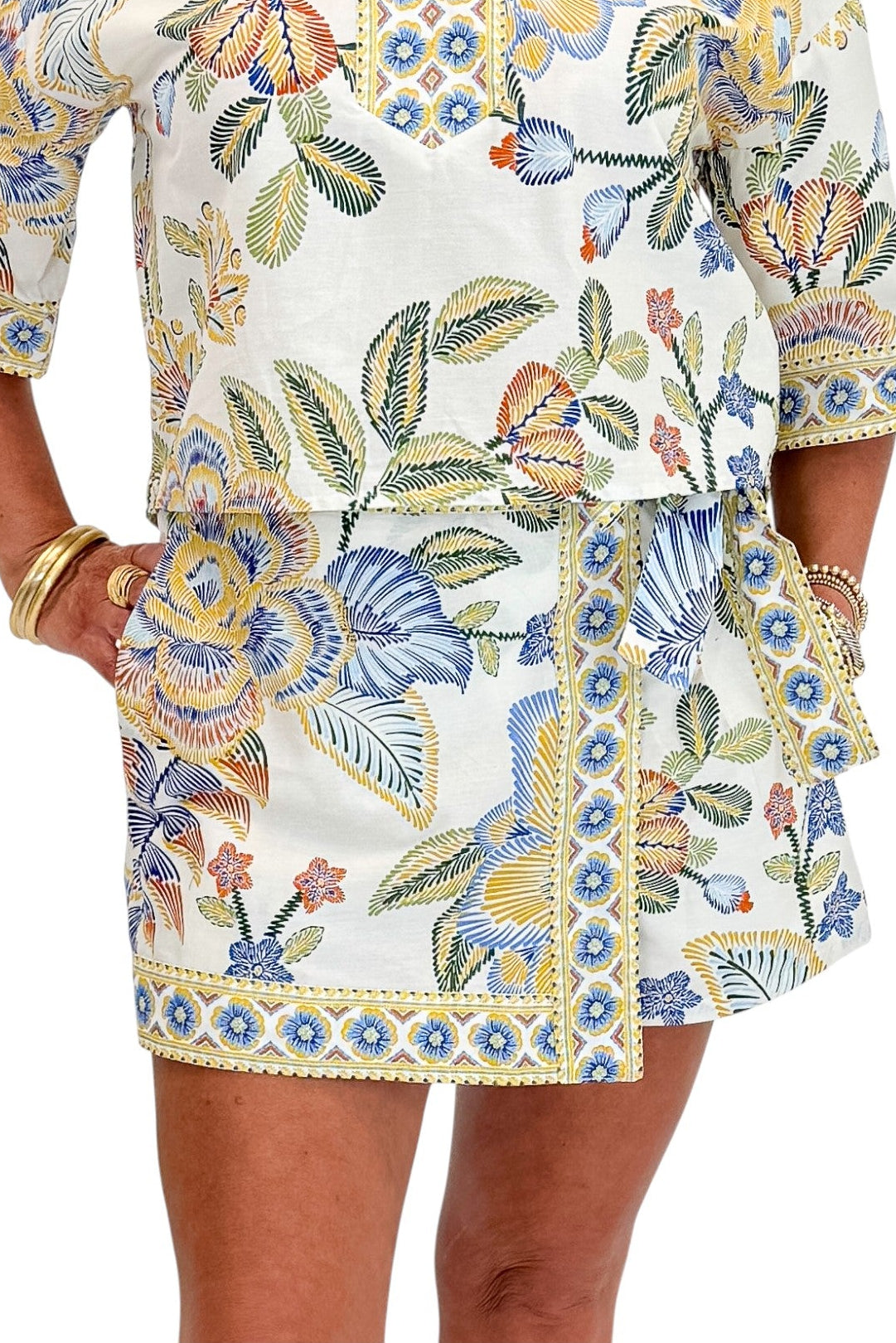 Front detail of woman wearing Swagger Boutique’s Blue &amp; Yellow Floral Print Wrap Skort by Entro with matching top against white studio background.