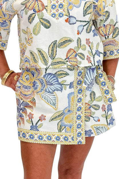 Front detail of woman wearing Swagger Boutique’s Blue &amp; Yellow Floral Print Wrap Skort by Entro with matching top against white studio background.