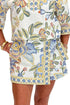 Front detail of woman wearing Swagger Boutique’s Blue & Yellow Floral Print Wrap Skort by Entro with matching top against white studio background.
