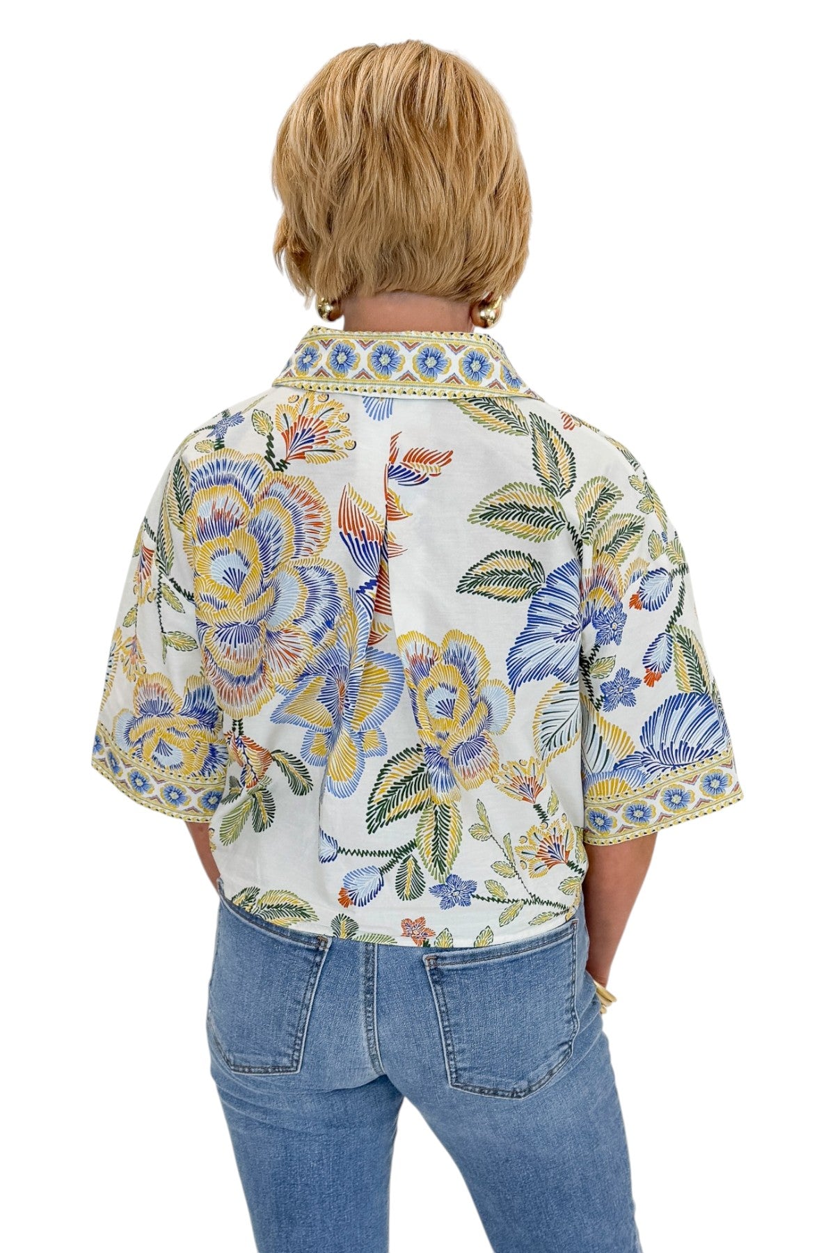 Back view of woman wearing Swagger Boutique’s Blue &amp; Yellow Floral Print Collared Top with jeans against white studio background.