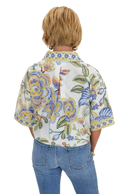 Back view of woman wearing Swagger Boutique’s Blue &amp; Yellow Floral Print Collared Top with jeans against white studio background.