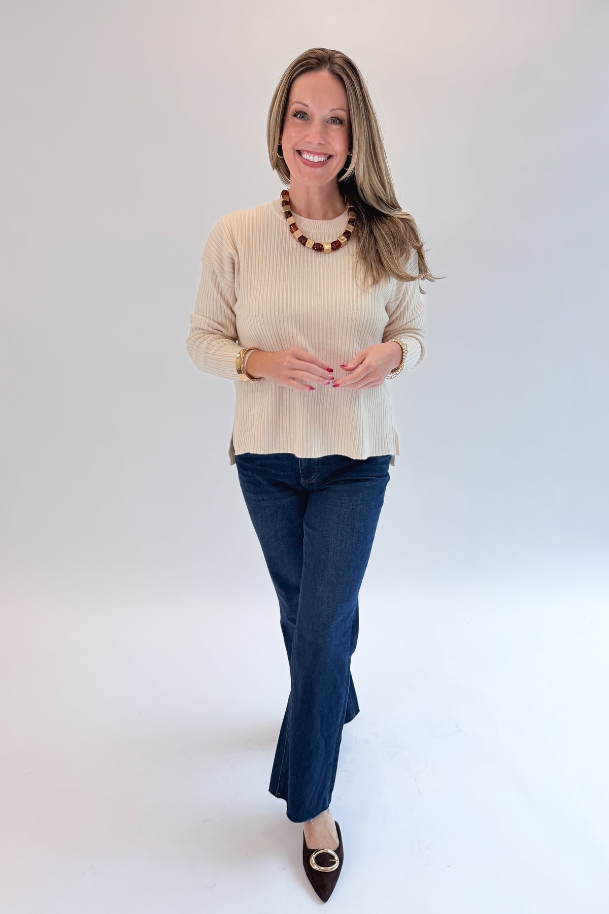 Front view of woman wearing Swagger Boutique’s Bone Ribbed Lightweight Sweater with jeans against white studio background.