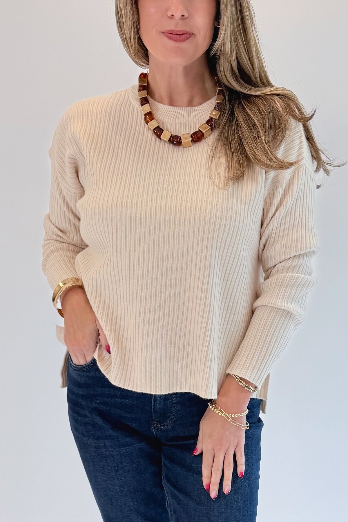 Front detail view of woman wearing Swagger Boutique’s Bone Ribbed Lightweight Sweater with jeans against white studio background.