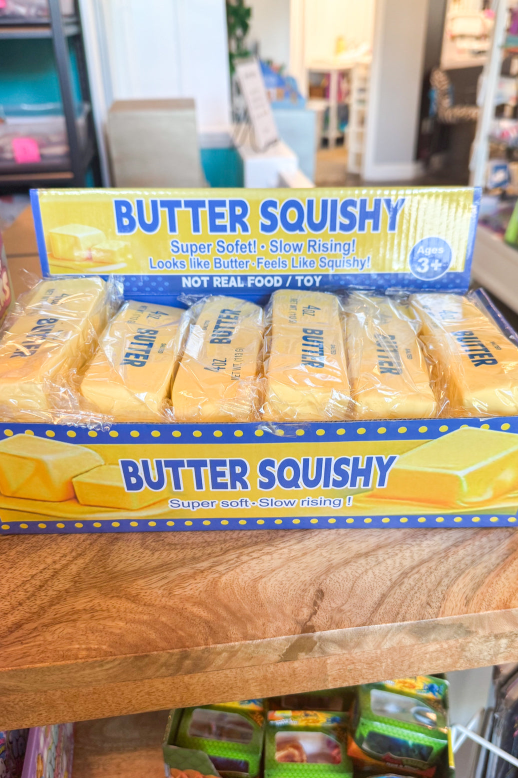 Box of Butter Squishy toys on a wooden shelf in a store setting