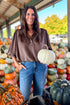 Front view of woman wearing Swagger Boutique’s Brown Bubble Hem Top With Buttons by Entro with jeans at a pumpkin patch.