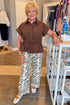 Front view of woman wearing Swagger Boutique’s Brown Cinched Waist Short Sleeve Top with zebra jeans at the store.