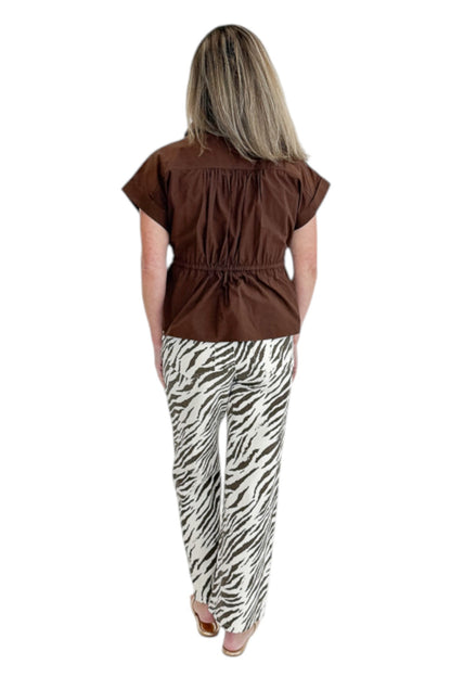 Back view of woman wearing Swagger Boutique’s Brown Cinched Waist Short Sleeve Top with zebra jeans against white studio background.