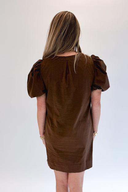 Back view of woman wearing Swagger Boutique’s Brown Embroidered Corduroy Dress with heels against white studio background.