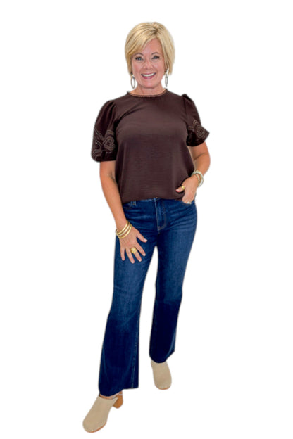 Front view of woman wearing Swagger Boutique’s Brown Embroidered Short Sleeve Top with jeans against white studio background.