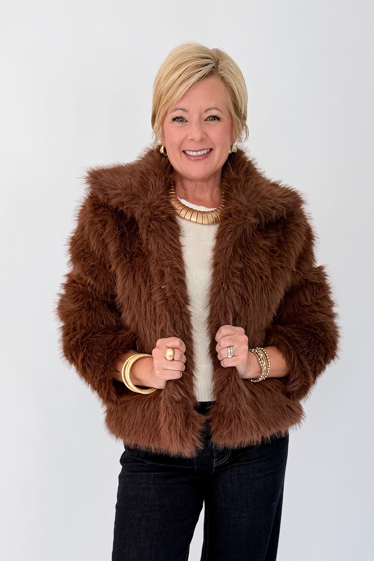 Front view of woman wearing Swagger Boutique’s Brown Faux Fur Jacket with jeans against white studio background.