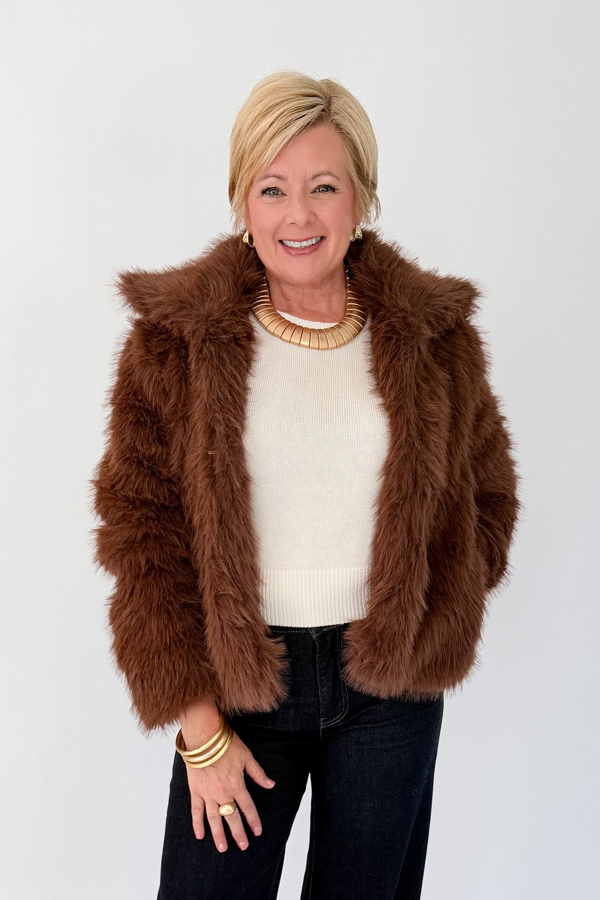 Front view of woman wearing Swagger Boutique’s Brown Faux Fur Jacket with jeans against white studio background.