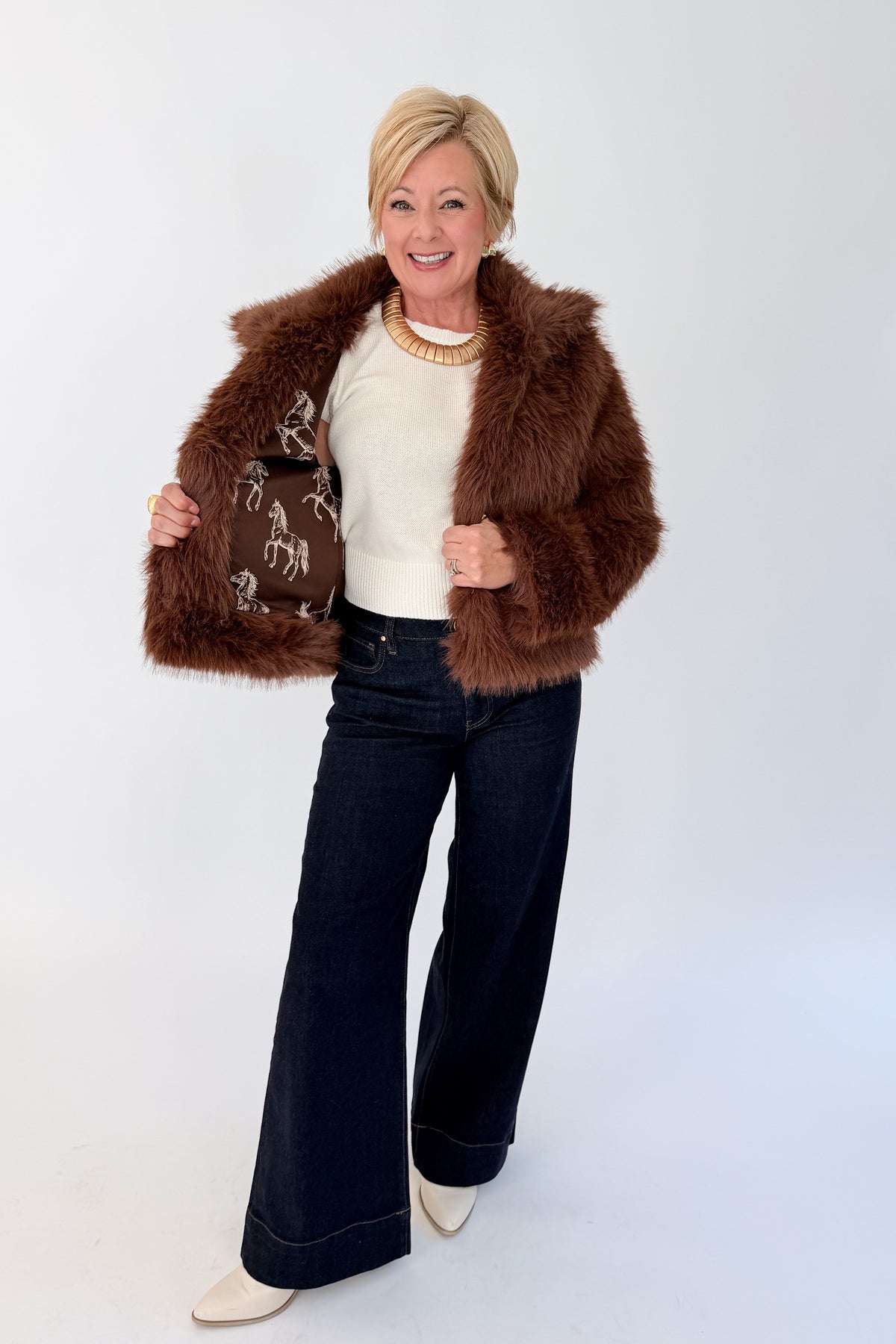 Front view of woman wearing Swagger Boutique’s Brown Faux Fur Jacket with jeans against white studio background.