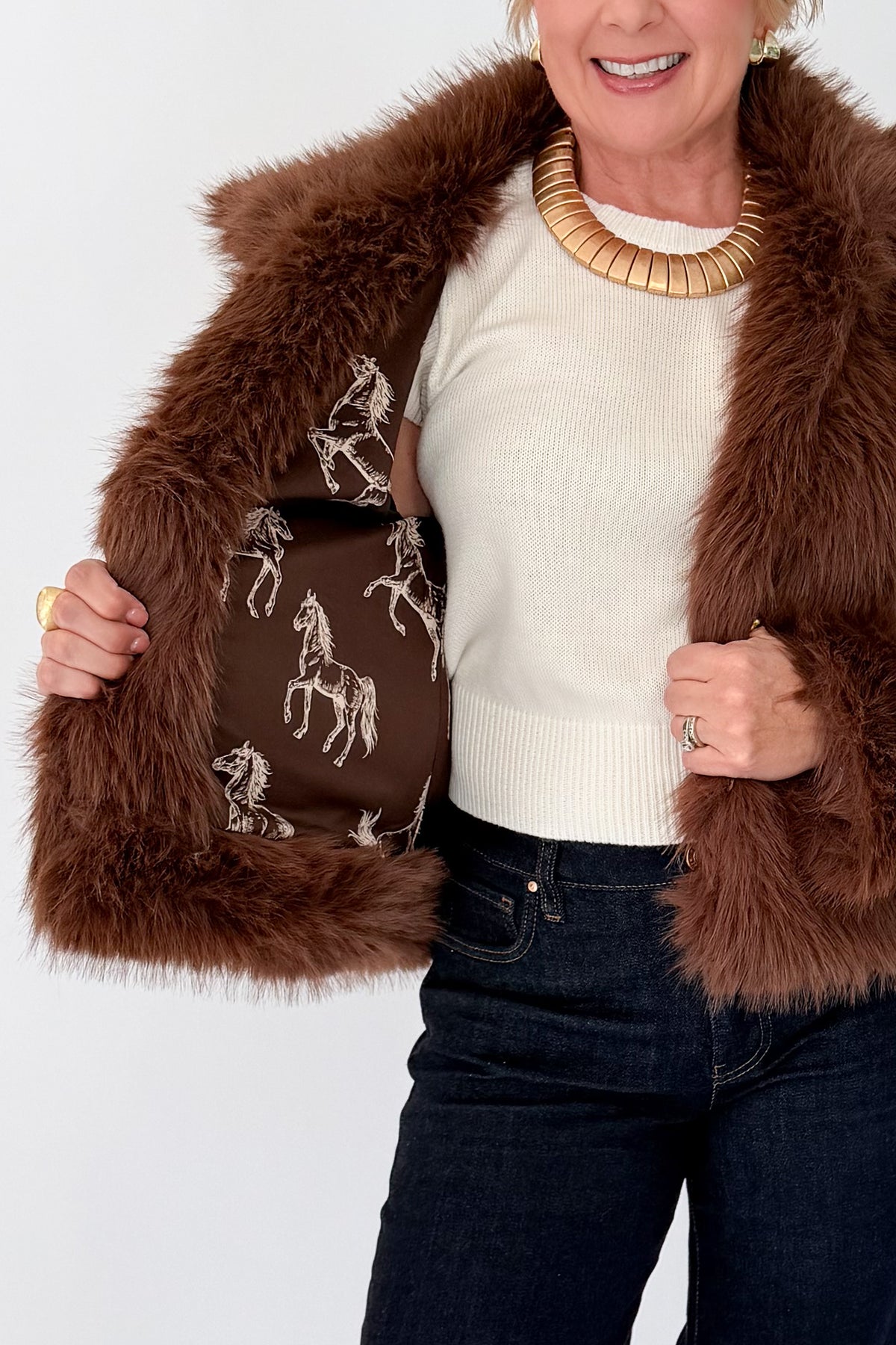 Front detail view of woman wearing Swagger Boutique’s Brown Faux Fur Jacket with jeans against white studio background.