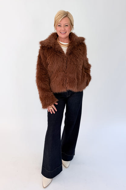 Front view of woman wearing Swagger Boutique’s Brown Faux Fur Jacket with jeans against white studio background.