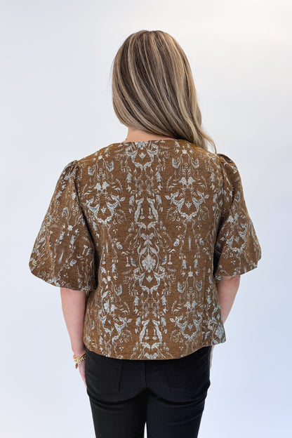Back view of woman wearing Swagger Boutique’s Brown Floral Corduroy Top with jeans against white studio background.
