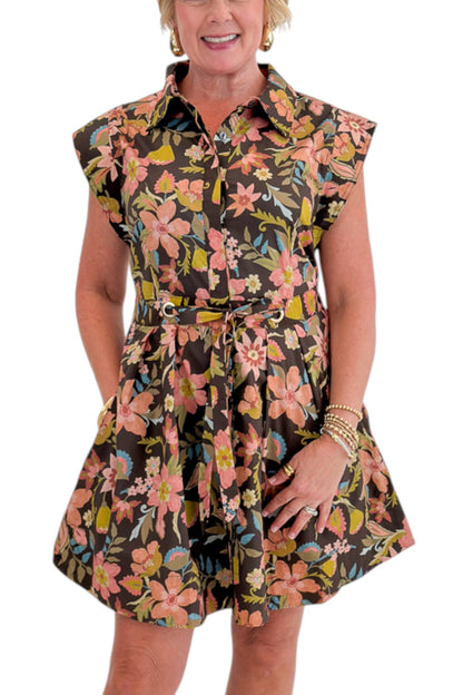Front detail view of woman wearing Swagger Boutique’s Brown Floral Tie Waist Mini Dress by Entro with clogs against white studio background.