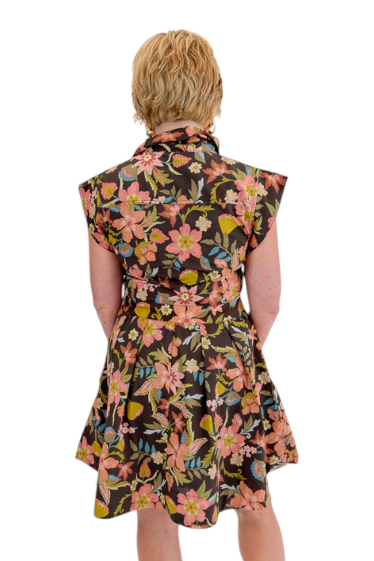 Back view of woman wearing Swagger Boutique’s Brown Floral Tie Waist Mini Dress by Entro with clogs against white studio background.
