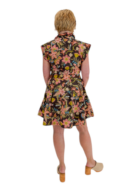 Back view of woman wearing Swagger Boutique’s Brown Floral Tie Waist Mini Dress by Entro with clogs against white studio background.