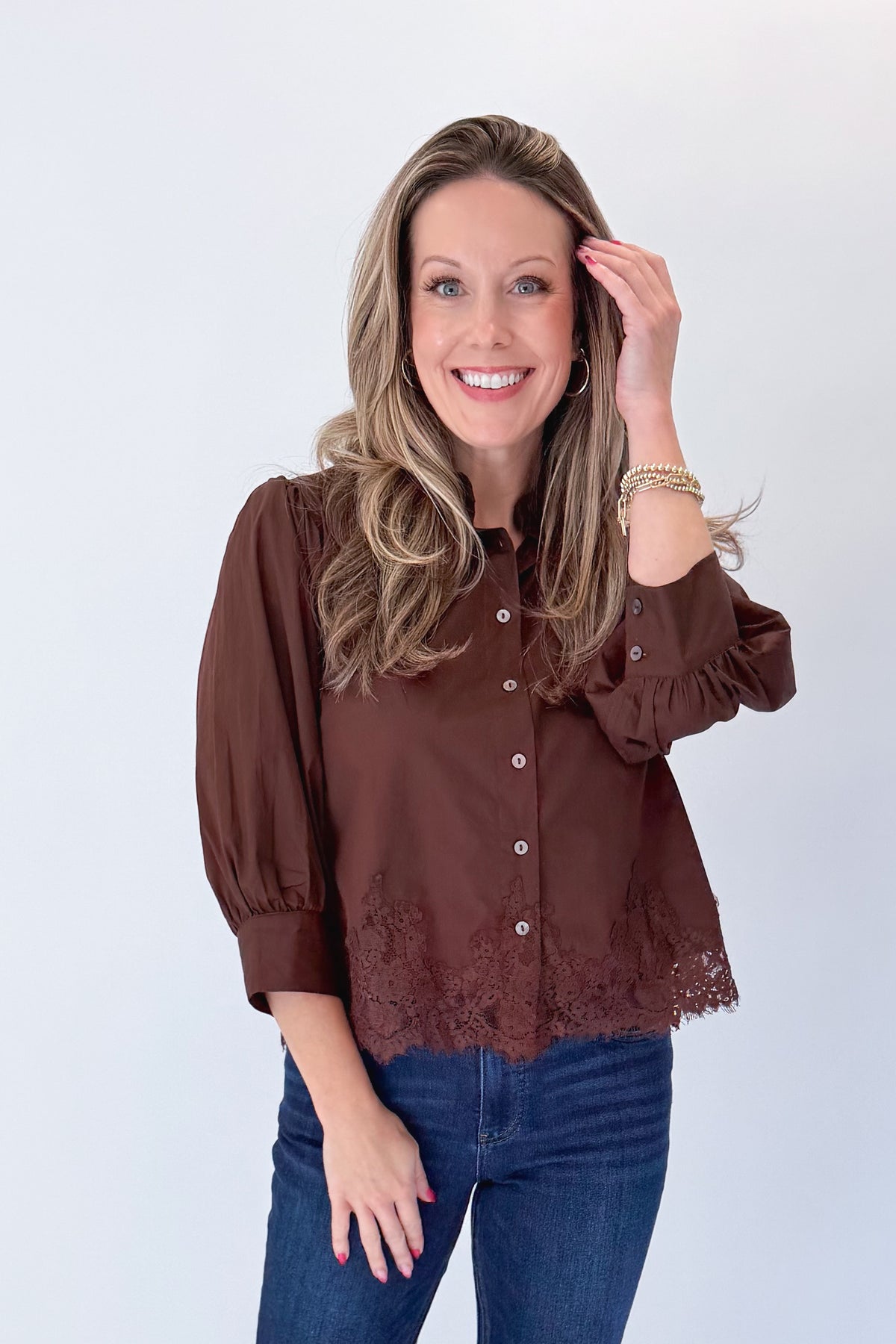 Front view of woman wearing Swagger Boutique’s Brown Lace Lined Button Up Top by Entro with jeans against white studio background.