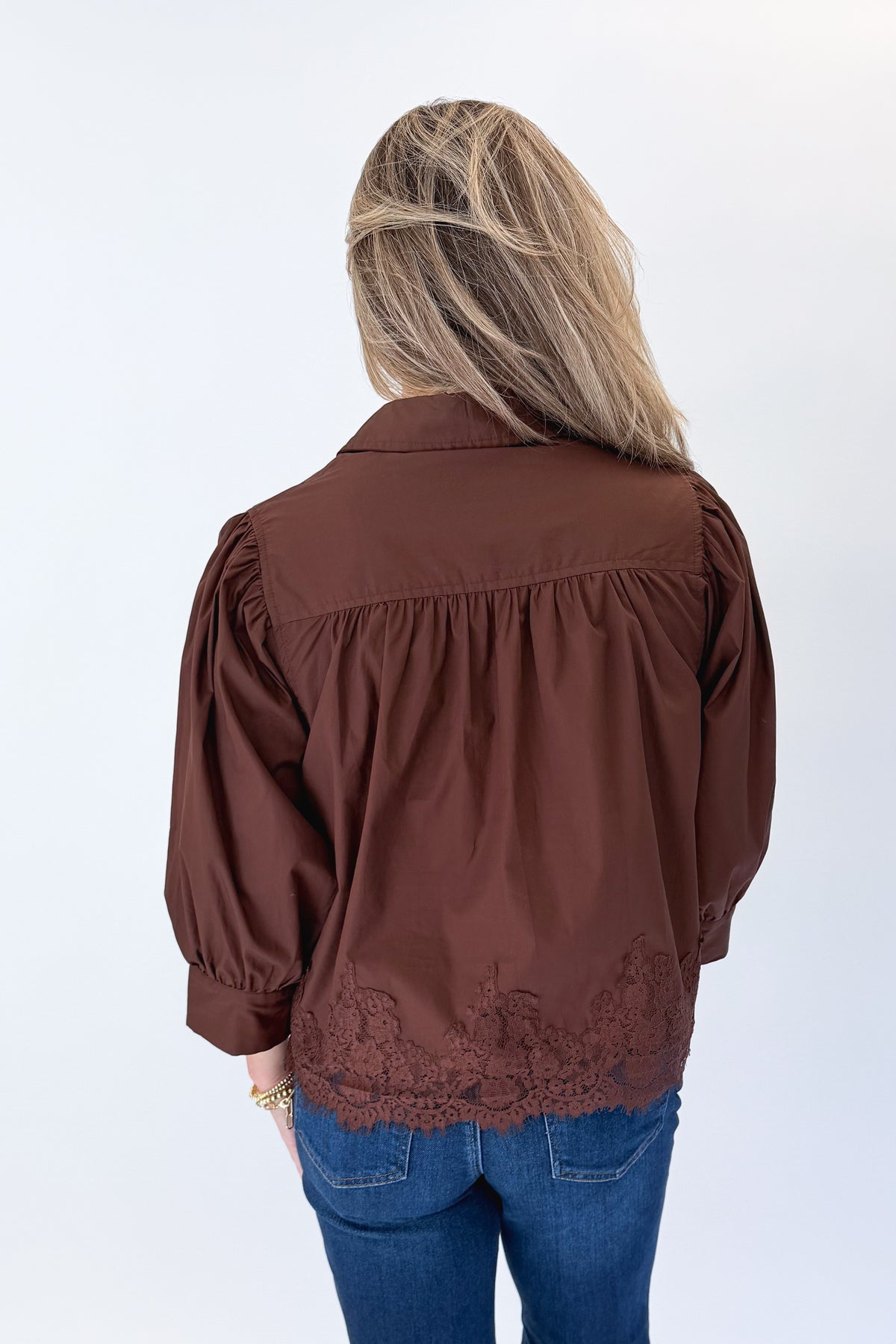 Back view of woman wearing Swagger Boutique’s Brown Lace Lined Button Up Top by Entro with jeans against white studio background.