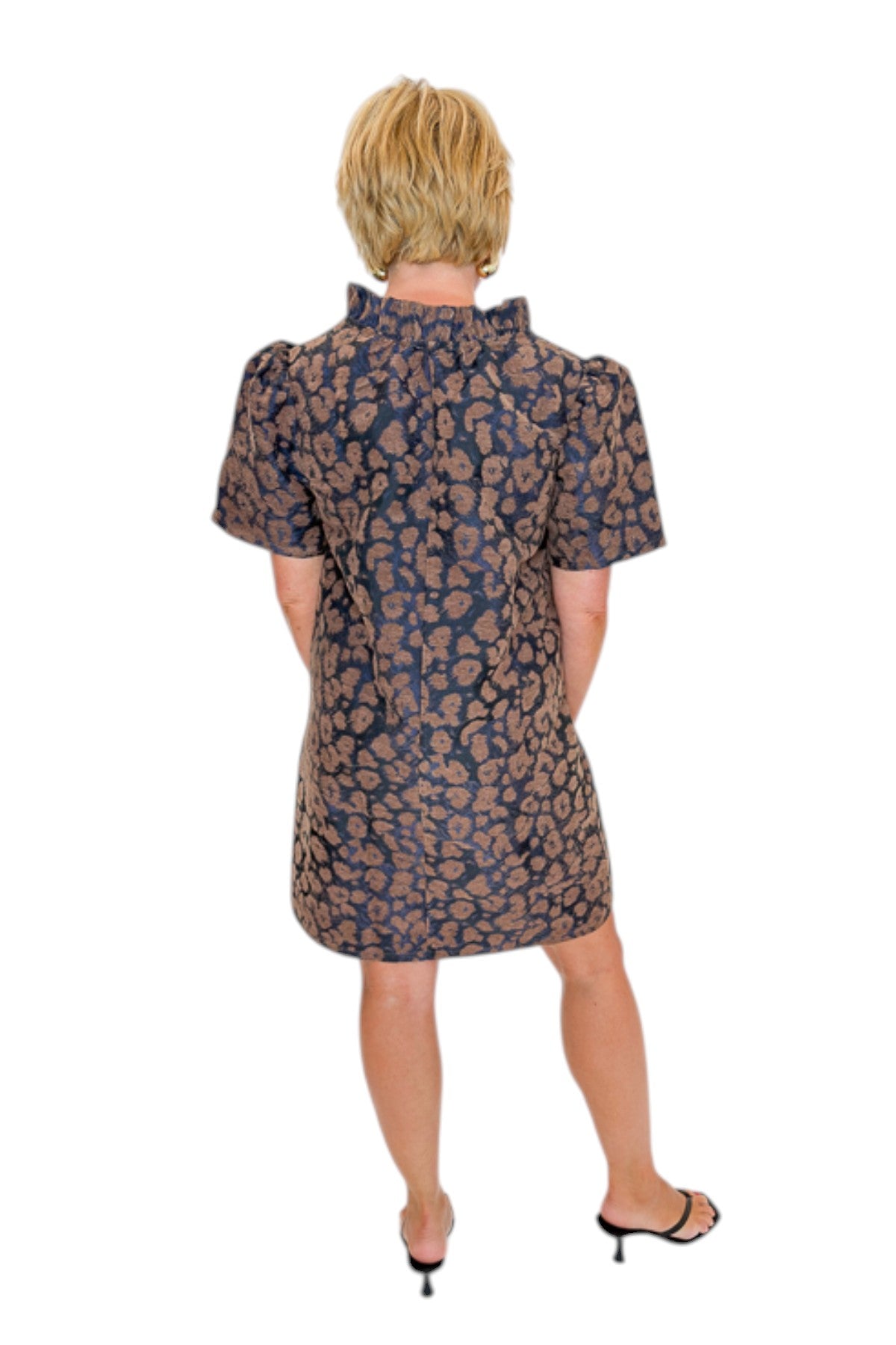 Back view of woman wearing Swagger Boutique’s Brown Leopard Velvet V-Neck Dress with heels against white studio background.