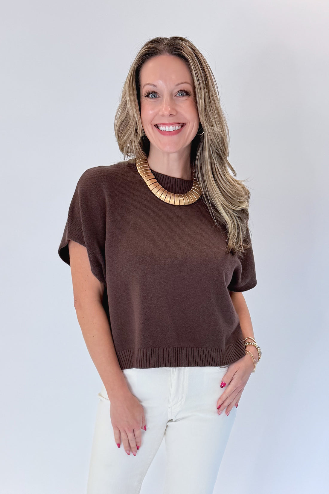 Front view of woman wearing Swagger Boutique’s Brown Light Weight Short Sleeve Sweater with jeans against white studio background.