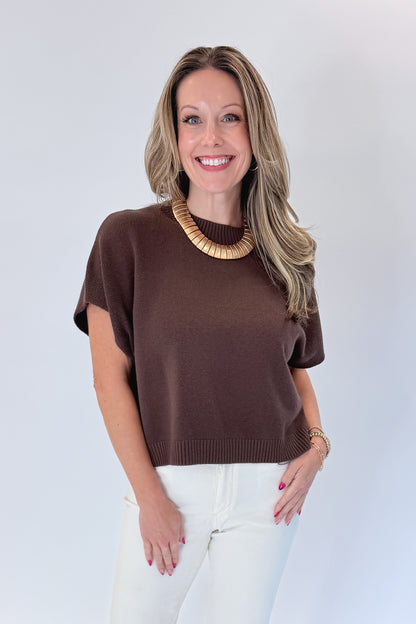 Front view of woman wearing Swagger Boutique’s Brown Light Weight Short Sleeve Sweater with jeans against white studio background.