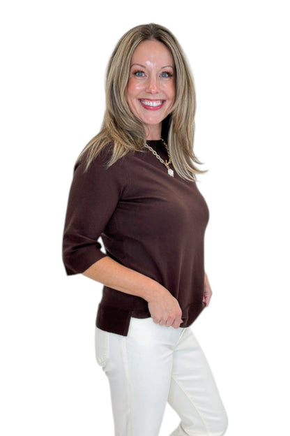 Side view of woman wearing Swagger Boutique’s Brown Lightweight Half Sleeve Sweater with jeans against white studio background.