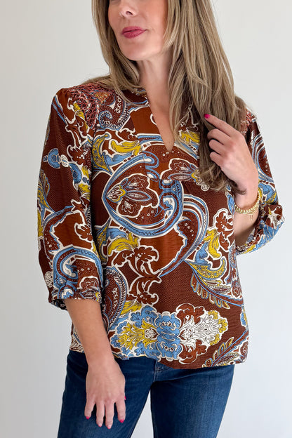 Front detail view of woman wearing Swagger Boutique’s Brown Paisley Print V-Neck Top with jeans against white studio background.