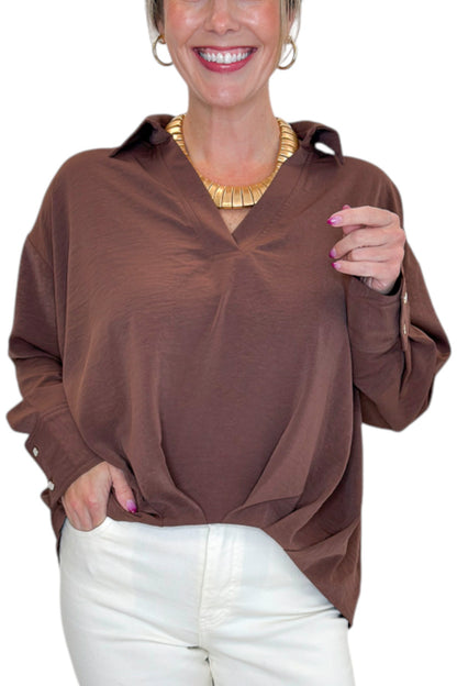Front detail view of woman wearing Swagger Boutique’s Brown Pleated Long Sleeve Top by Entro with jeans against white studio background.
