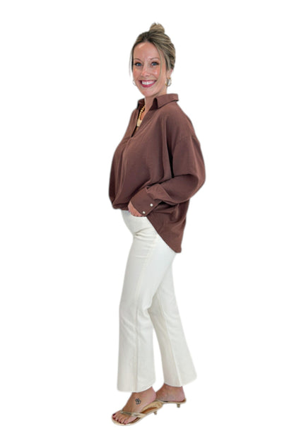 Side view of woman wearing Swagger Boutique’s Brown Pleated Long Sleeve Top by Entro with jeans against white studio background.
