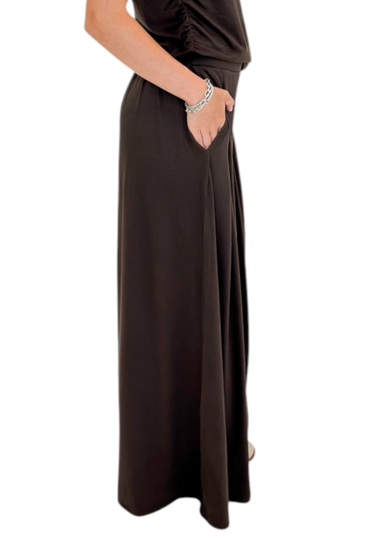 Side detail view of woman wearing Swagger Boutique’s Brown Pleated Wide Leg Pants with Brown Rouched Side Tank against white studio background.