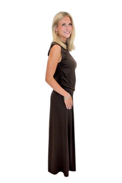 Side view of woman wearing Swagger Boutique’s Brown Pleated Wide Leg Pants with Brown Rouched Side Tank against white studio background.