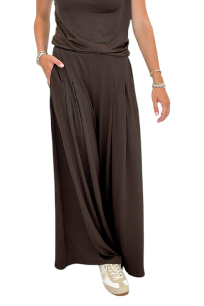 Front detail view of woman wearing Swagger Boutique’s Brown Pleated Wide Leg Pants with Brown Rouched Side Tank against white studio background.