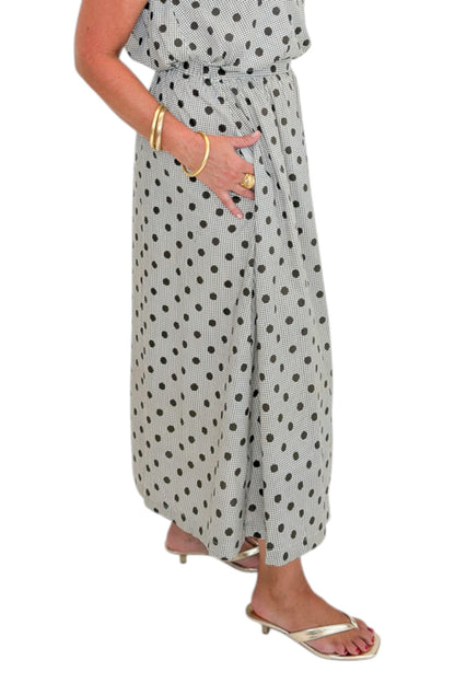 Side detail view of woman wearing Swagger Boutique’s Brown Polka Dot Bubble Hem Tank and Midi Skirt by Entro against white studio background.