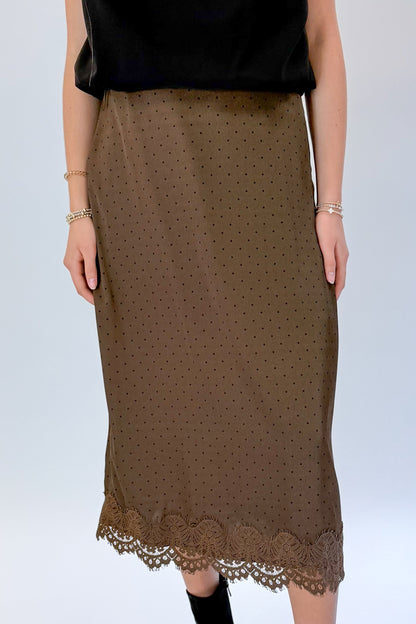 Front detail view of woman wearing Swagger Boutique’s Brown Polka Dot Lace Lined Satin Skirt by Entro with Black Satin Cowlneck Sleeveless Top against white studio background.