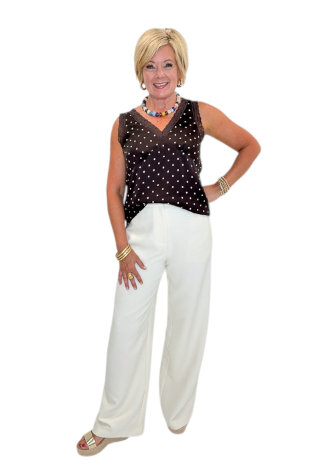 Front view of woman wearing Swagger Boutique’s Brown Polka Dot Lace Trim Tank with Cream Lace Lined Pants against white studio background.