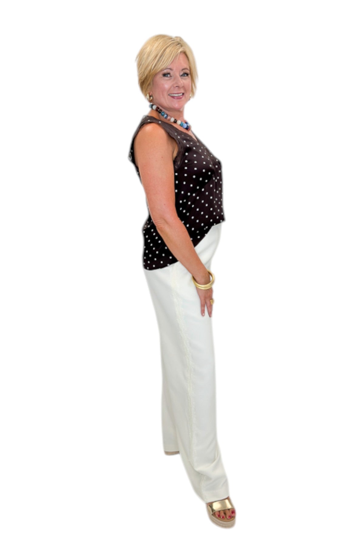 Side view of woman wearing Swagger Boutique’s Brown Polka Dot Lace Trim Tank with Cream Lace Lined Pants against white studio background.