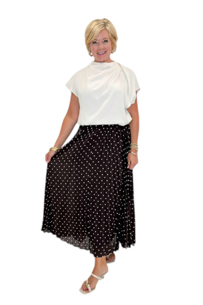 Front view of woman wearing Swagger Boutique’s Brown Polka Dot Pleated Skirt with top against white studio background.