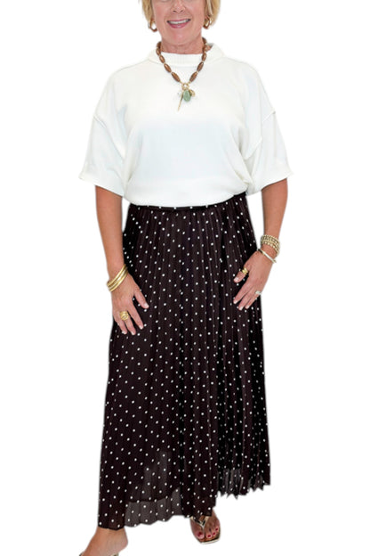 Front detail view of woman wearing Swagger Boutique’s Brown Polka Dot Pleated Skirt with top against white studio background.