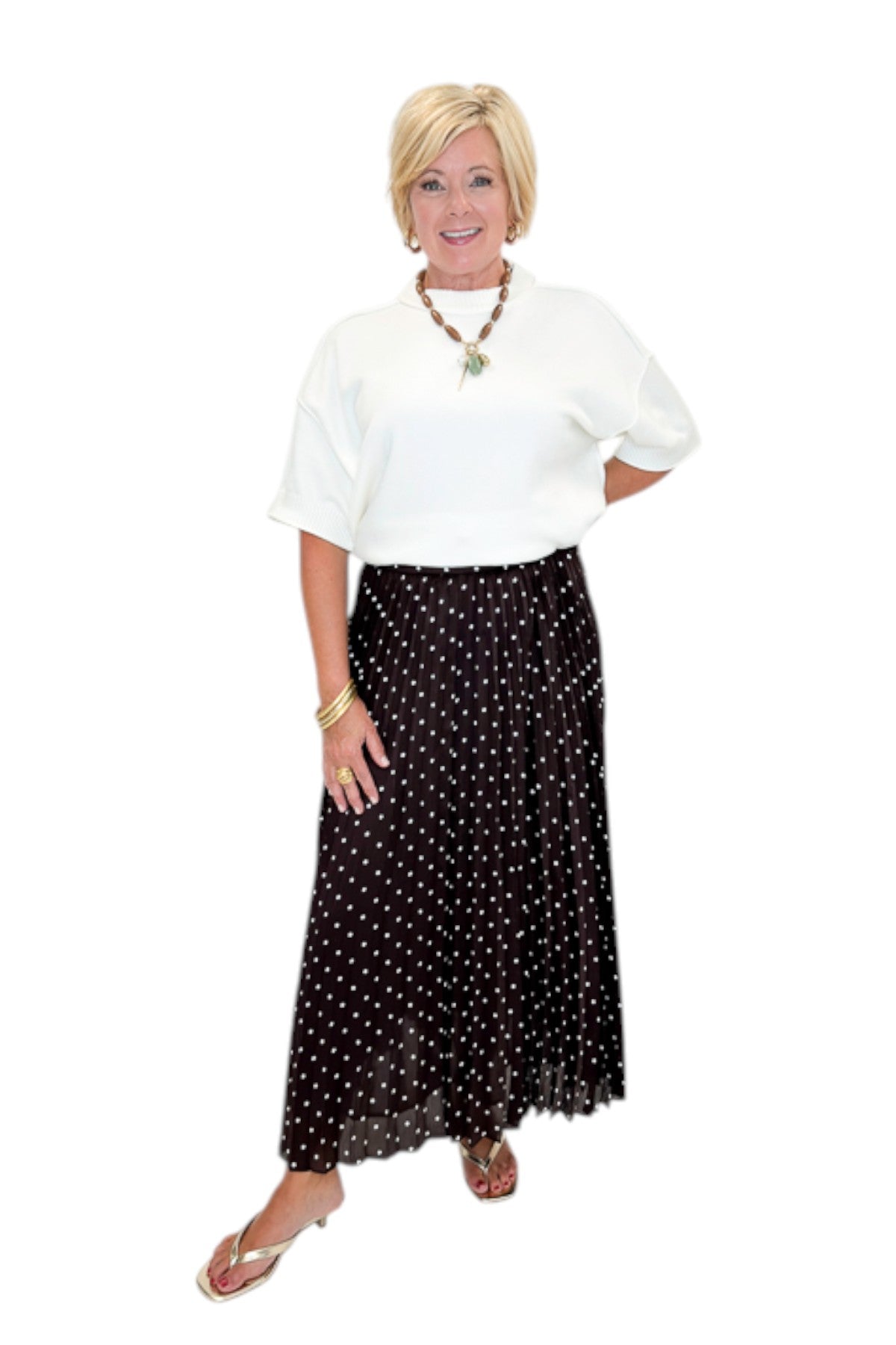 Front view of woman wearing Swagger Boutique’s Brown Polka Dot Pleated Skirt with top against white studio background.