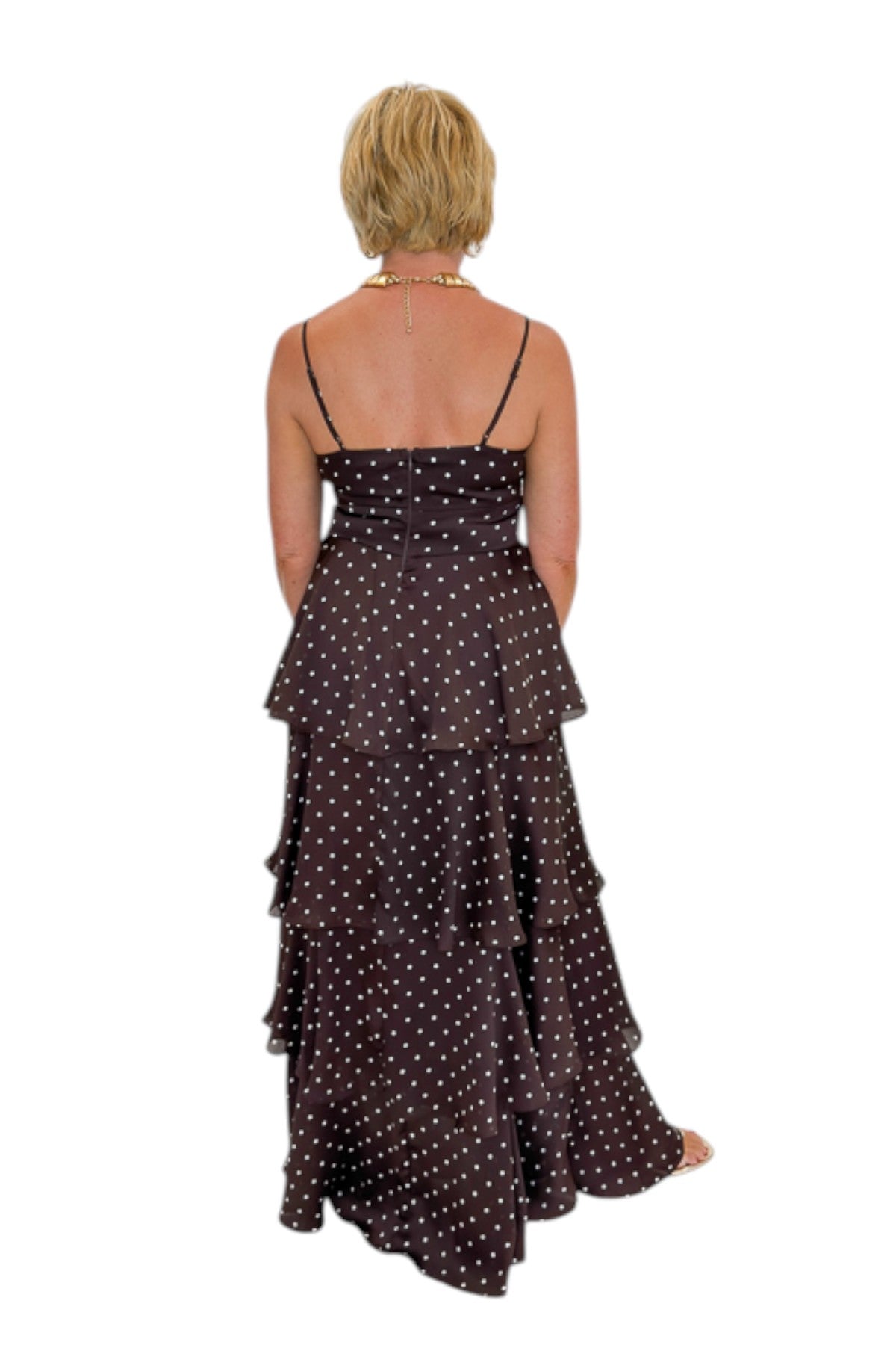 Back view of woman wearing Swagger Boutique’s Brown Polka Dot Tiered Maxi Dress with heels against white studio background.