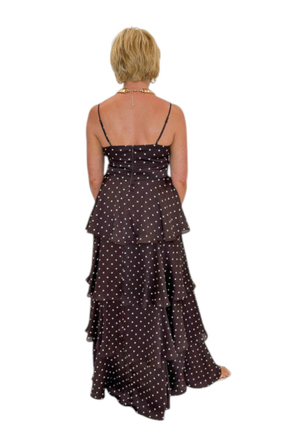 Back view of woman wearing Swagger Boutique’s Brown Polka Dot Tiered Maxi Dress with heels against white studio background.