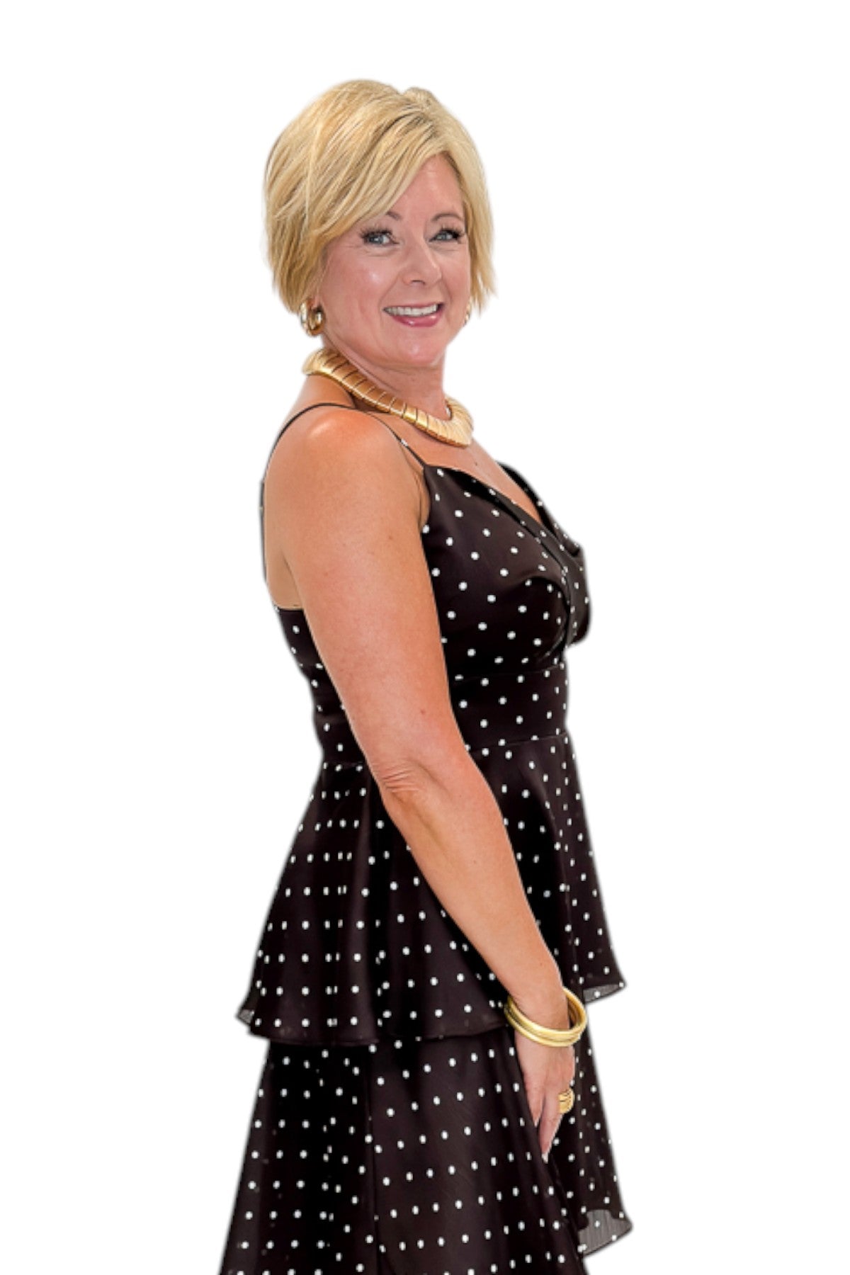 Side detail view of woman wearing Swagger Boutique’s Brown Polka Dot Tiered Maxi Dress with heels against white studio background.