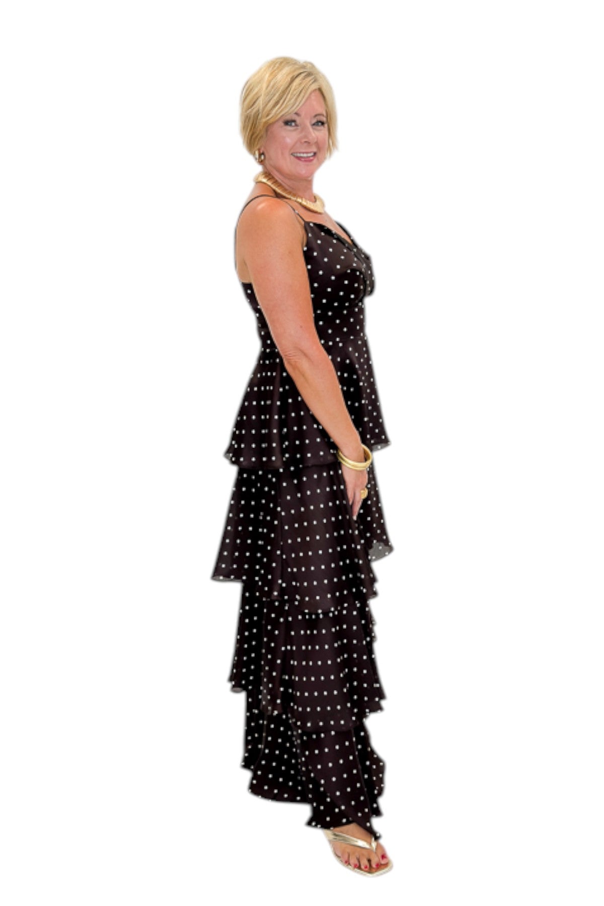 Side view of woman wearing Swagger Boutique’s Brown Polka Dot Tiered Maxi Dress with heels against white studio background.