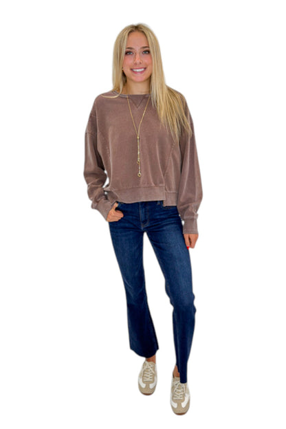 Front view of woman wearing Swagger Boutique’s Brown Ribbed Detail Sweatshirt with jeans against white studio background.